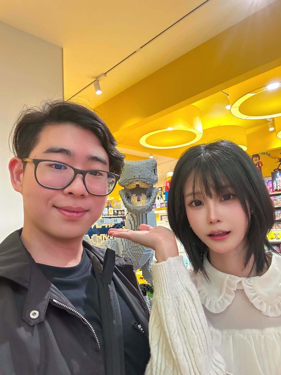 Posing in a LEGO store with a brick dinosaur behind them