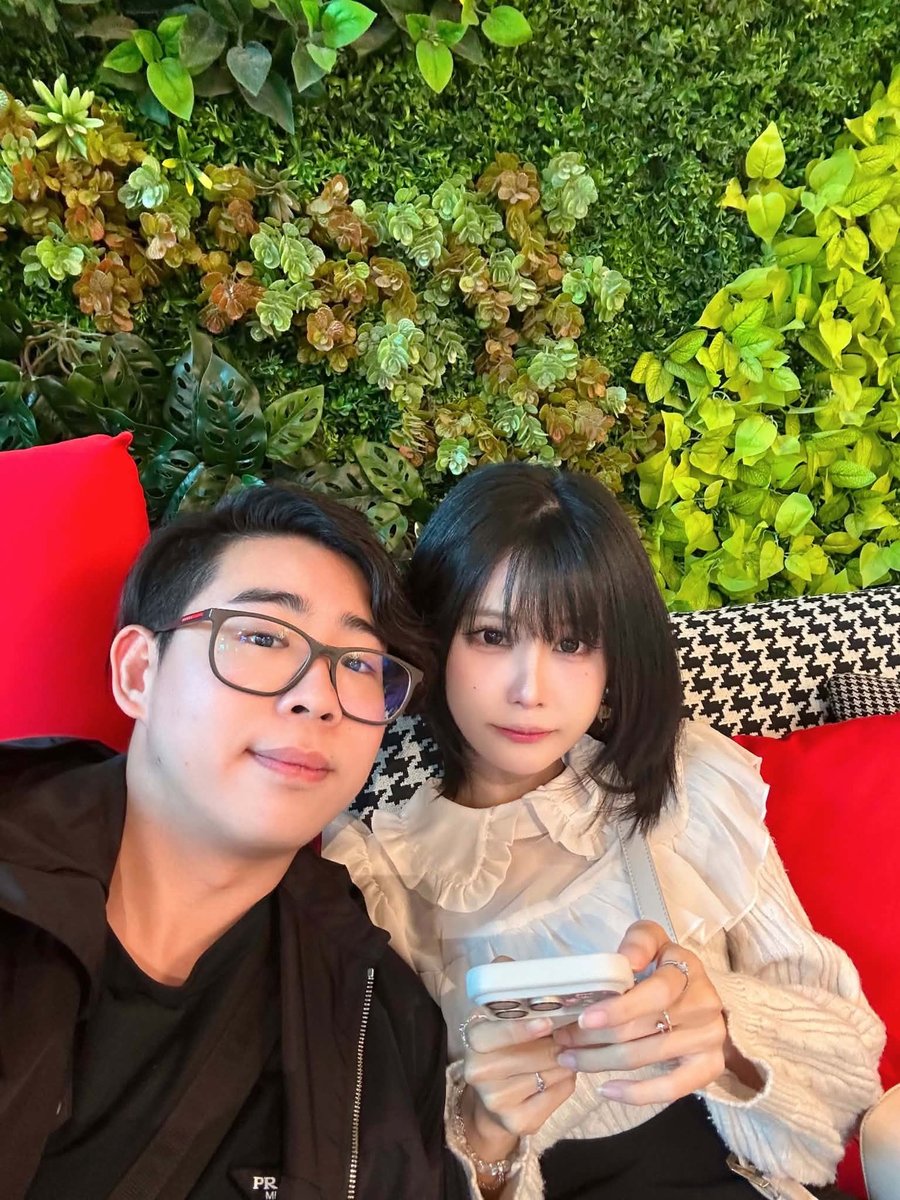 Sitting together on a red sofa in front of a plant wall